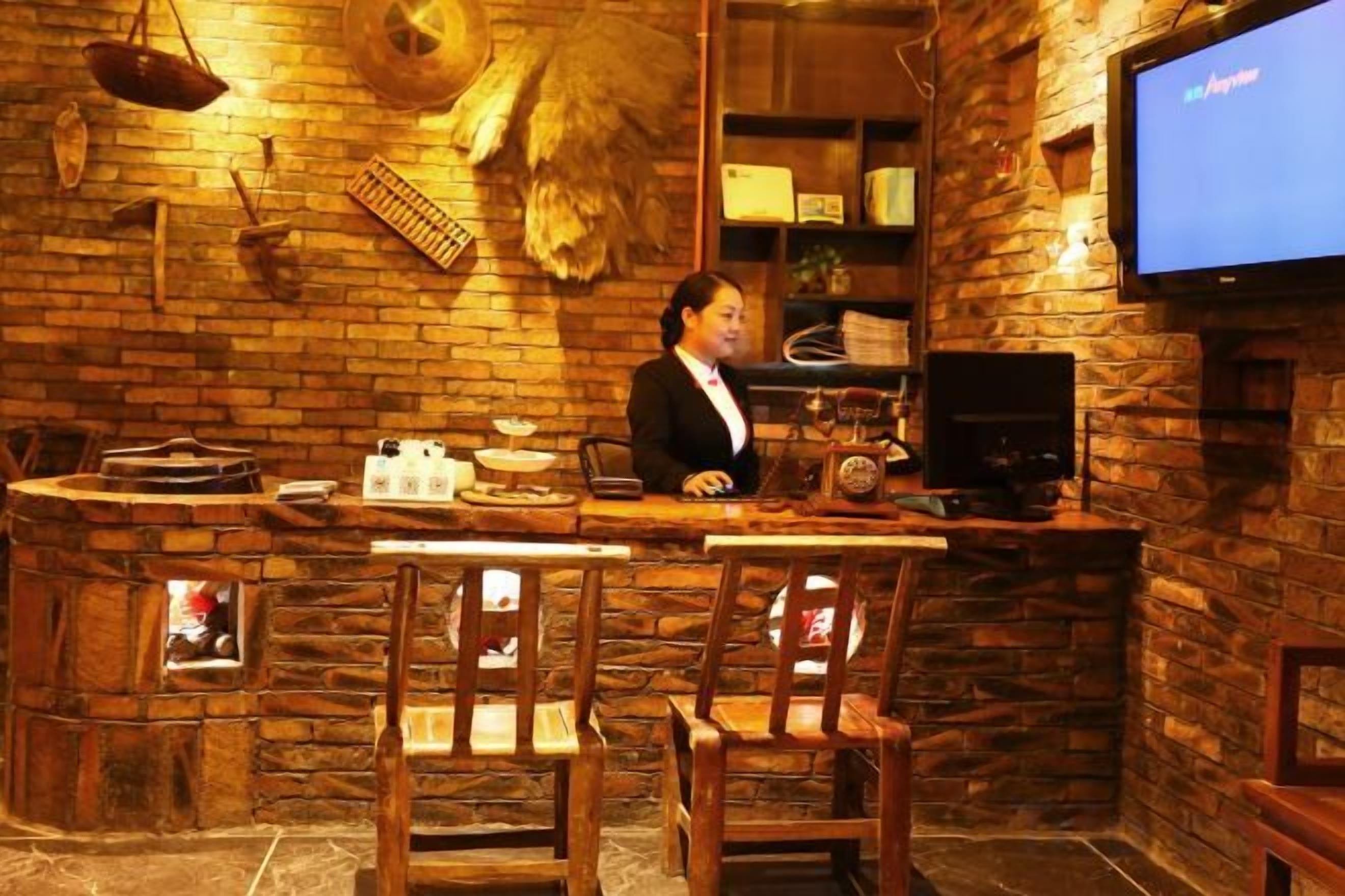Zona de bar con un cantinero, mostrador de madera, taburetes y una pantalla de televisión.