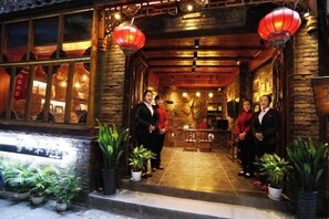 Un ristorante tradizionale cinese caratterizzato da architettura in legno, lanterne rosse e piante in vaso.