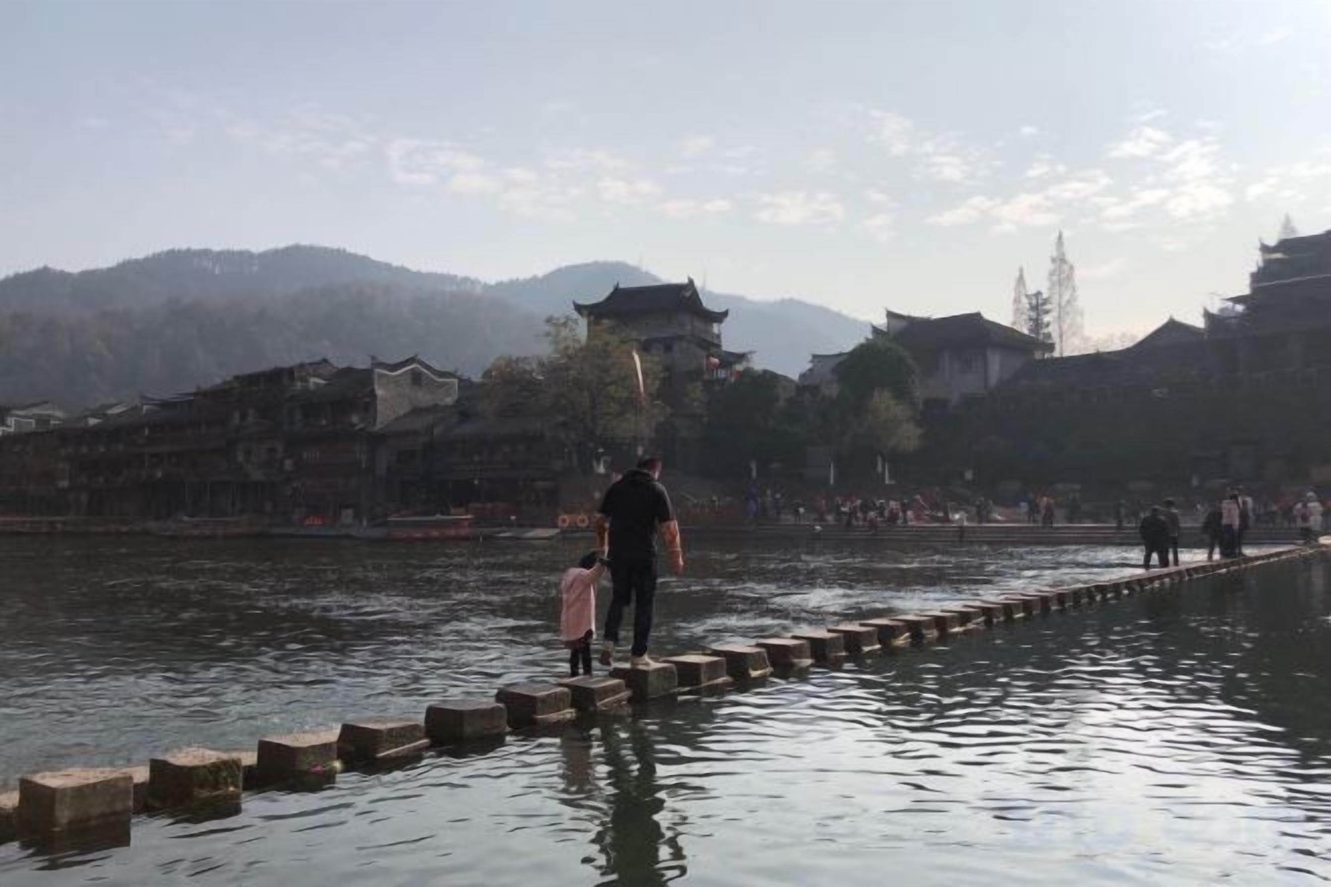 A riverside walkway with traditional architecture in the background.