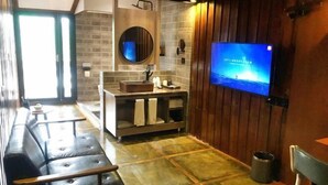 A modern bathroom with a TV, a sink, a mirror, and a wooden wall. - Dengnilai Inn (Fenghuang County)