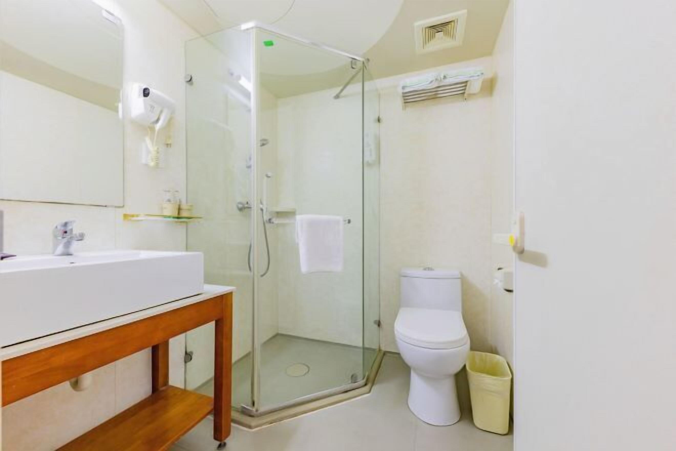 Un baño con ducha de vidrio, lavamanos blanco y retrete.