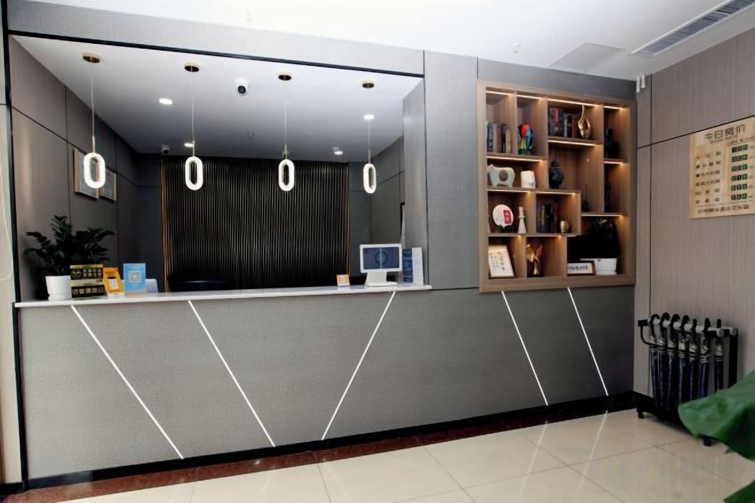 A reception area with a counter, a computer monitor, and a wall-mounted menu board.