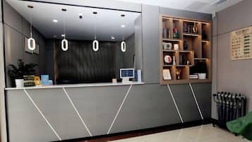 Un área de recepción con mostrador, un monitor de ordenador y un panel de menú en la pared.