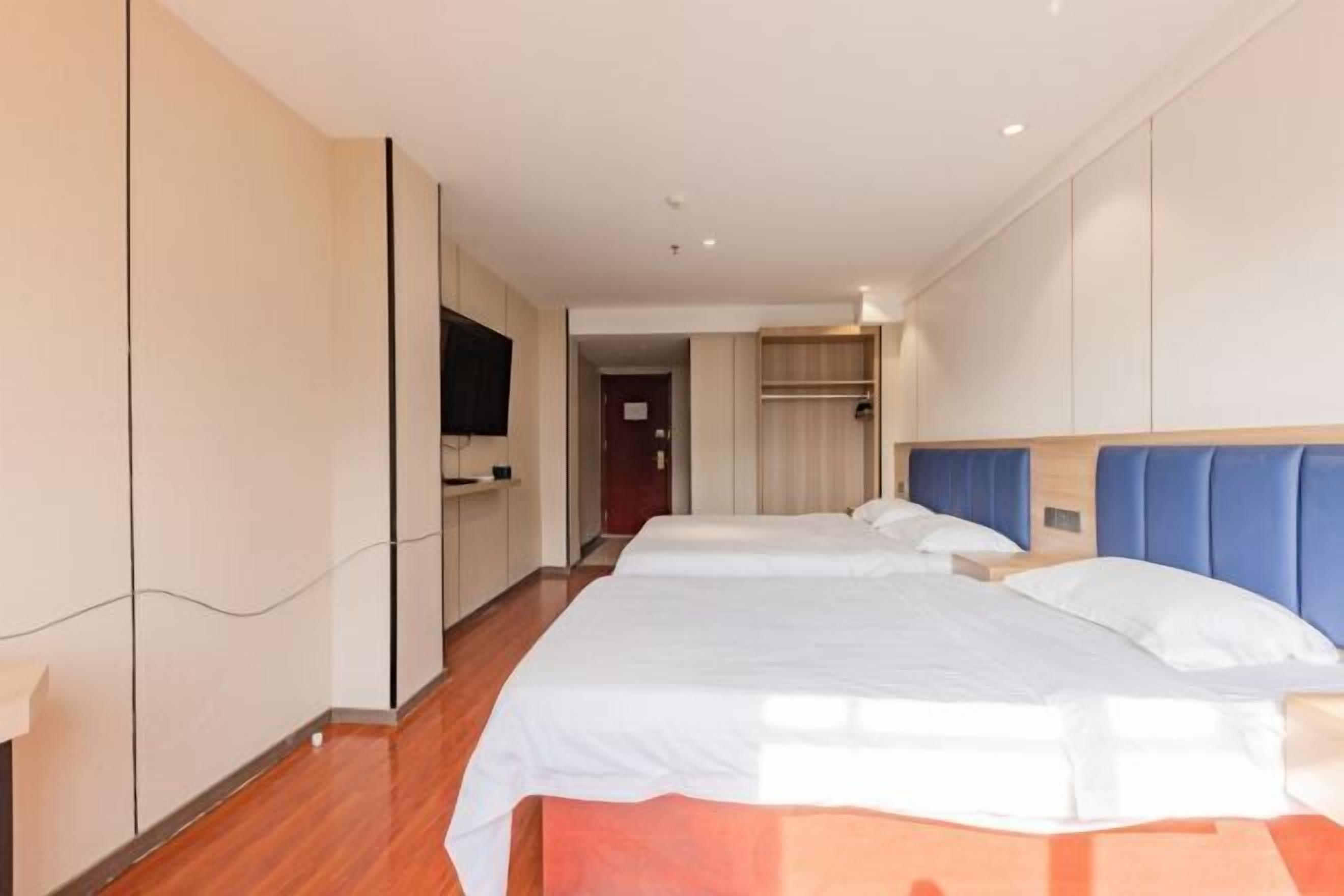 A hotel room with two beds, a TV, and a wardrobe.
