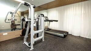 A gym with a treadmill, weight machines, and a mirror. - Elong Anyun Hotel (Nantong Haohe Scenic Area Zhongxiu West Road Subway Station) (Nantong)