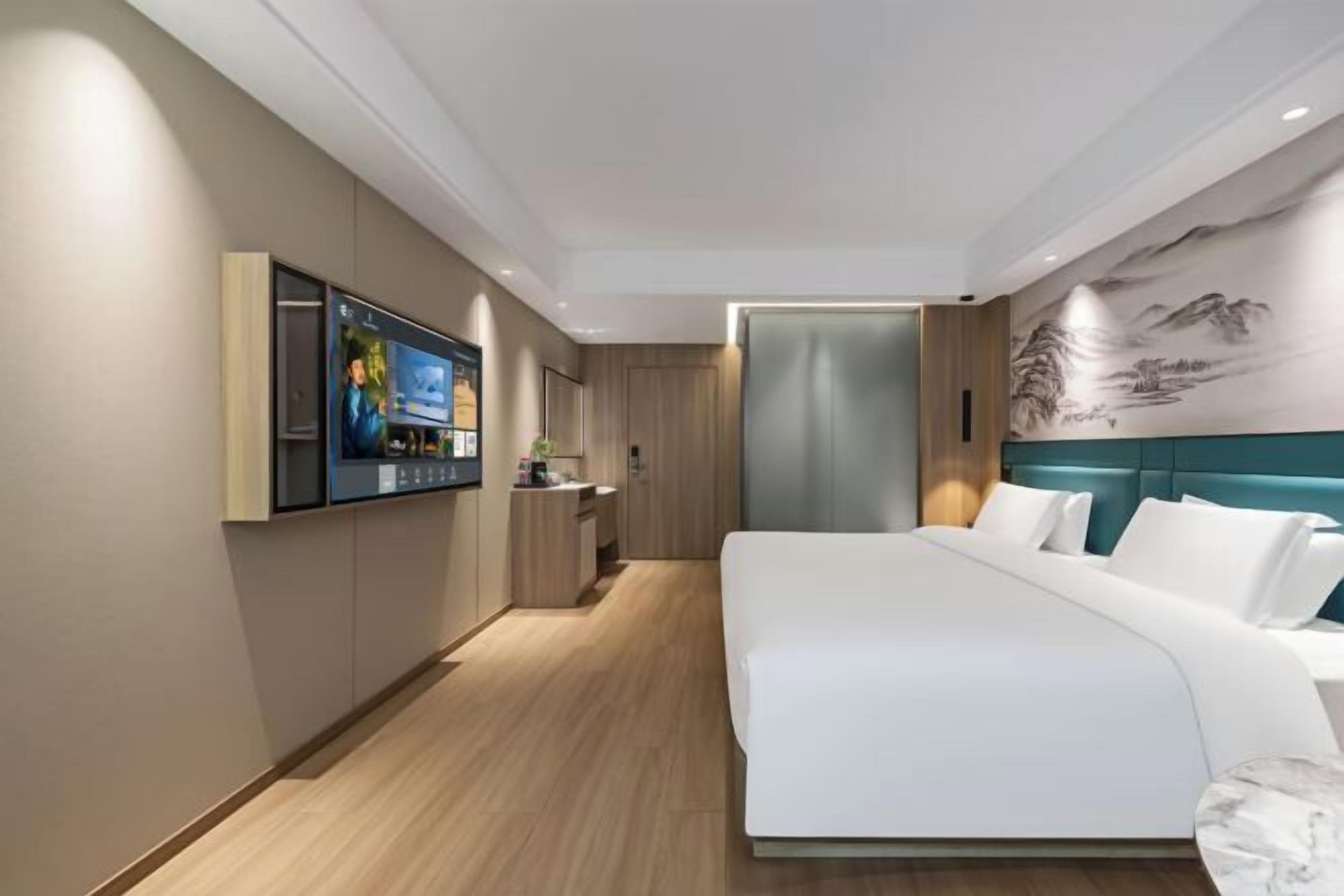 Une chambre d’hôtel moderne dotée d’un grand lit, d’un téléviseur fixé au mur et d’une fresque murale décorative.