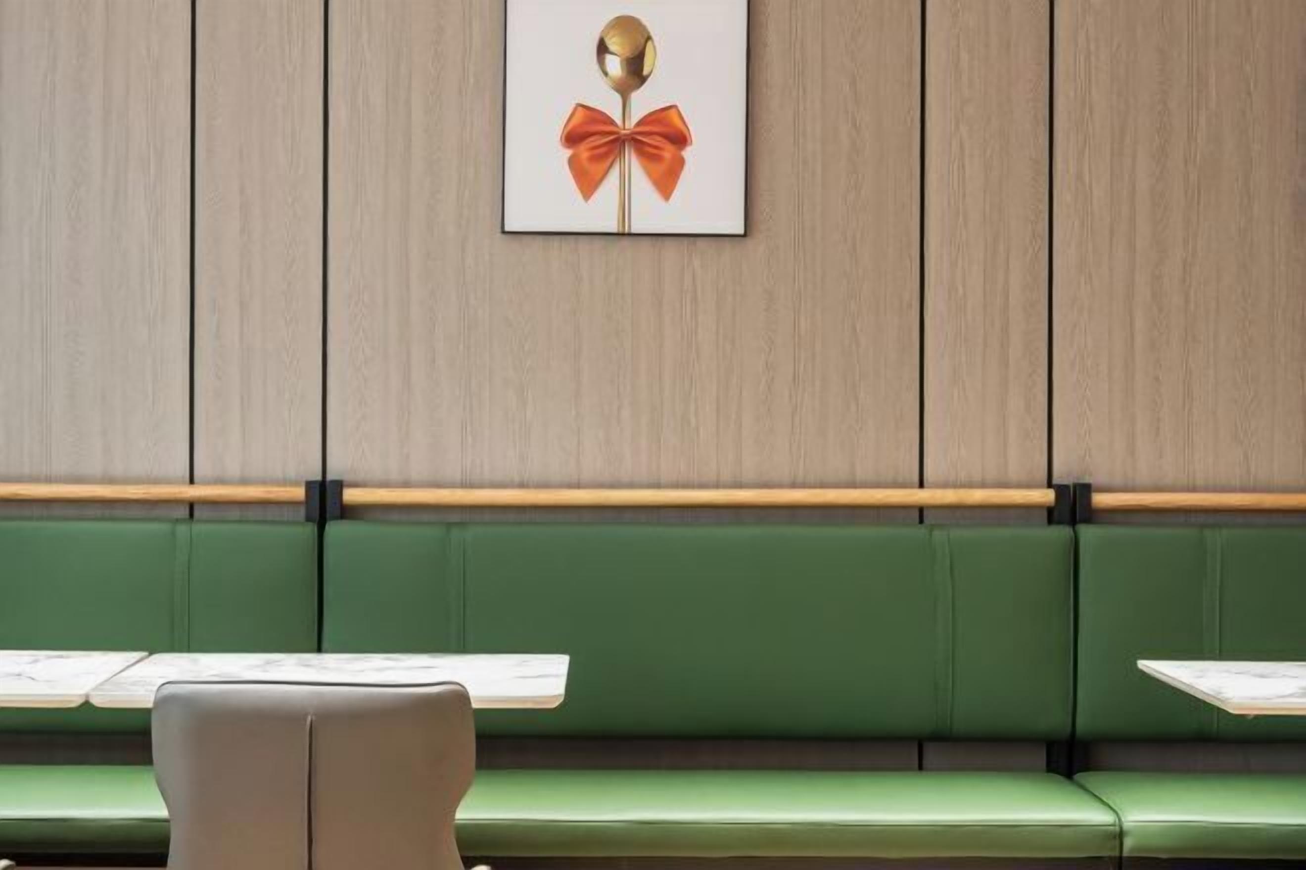 A green upholstered bench with a wooden table in front.