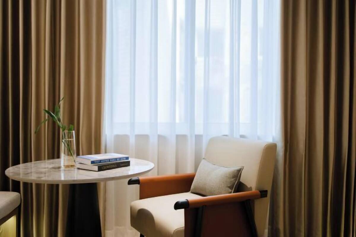 Una habitación con una mesa redonda, una silla y una ventana con cortinas.