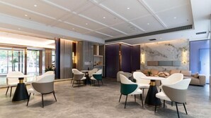 A modern hotel lobby with a seating area, a bar, and a large window providing a view of the outdoors. - Elong Anyun Hotel (Nantong Haohe Scenic Area Zhongxiu West Road Subway Station) (Nantong)