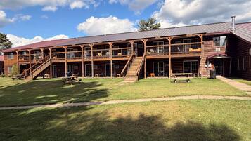 A two-story wooden building with a covered outdoor seating area and a staircase leading to the upper level.