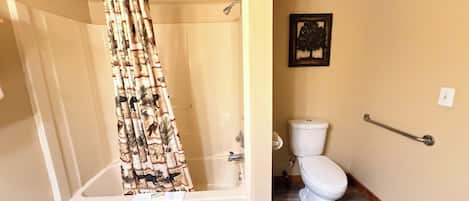 Une salle de bain équipée d’une baignoire, de toilettes, d’un rideau de douche et d’un porte-serviettes.