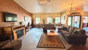 A spacious lobby with a fireplace, sofas, a coffee table, and a television.