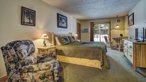 A cozy bedroom with a bed, a chair, a desk, and a television. - Eagle River Inn and Resort  (Eagle River)