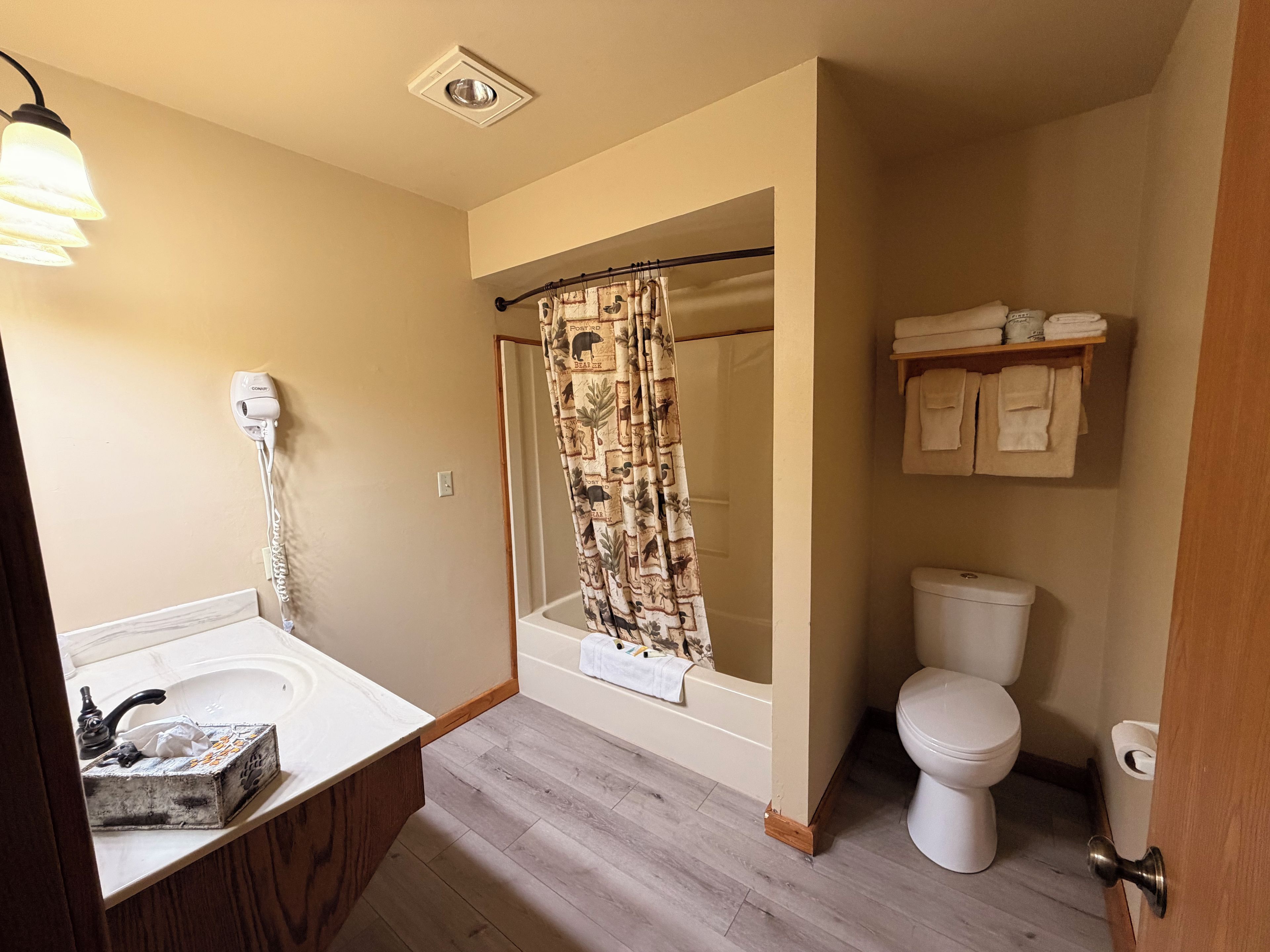 A bathroom with a bathtub, toilet, shower curtain, and a towel rack.