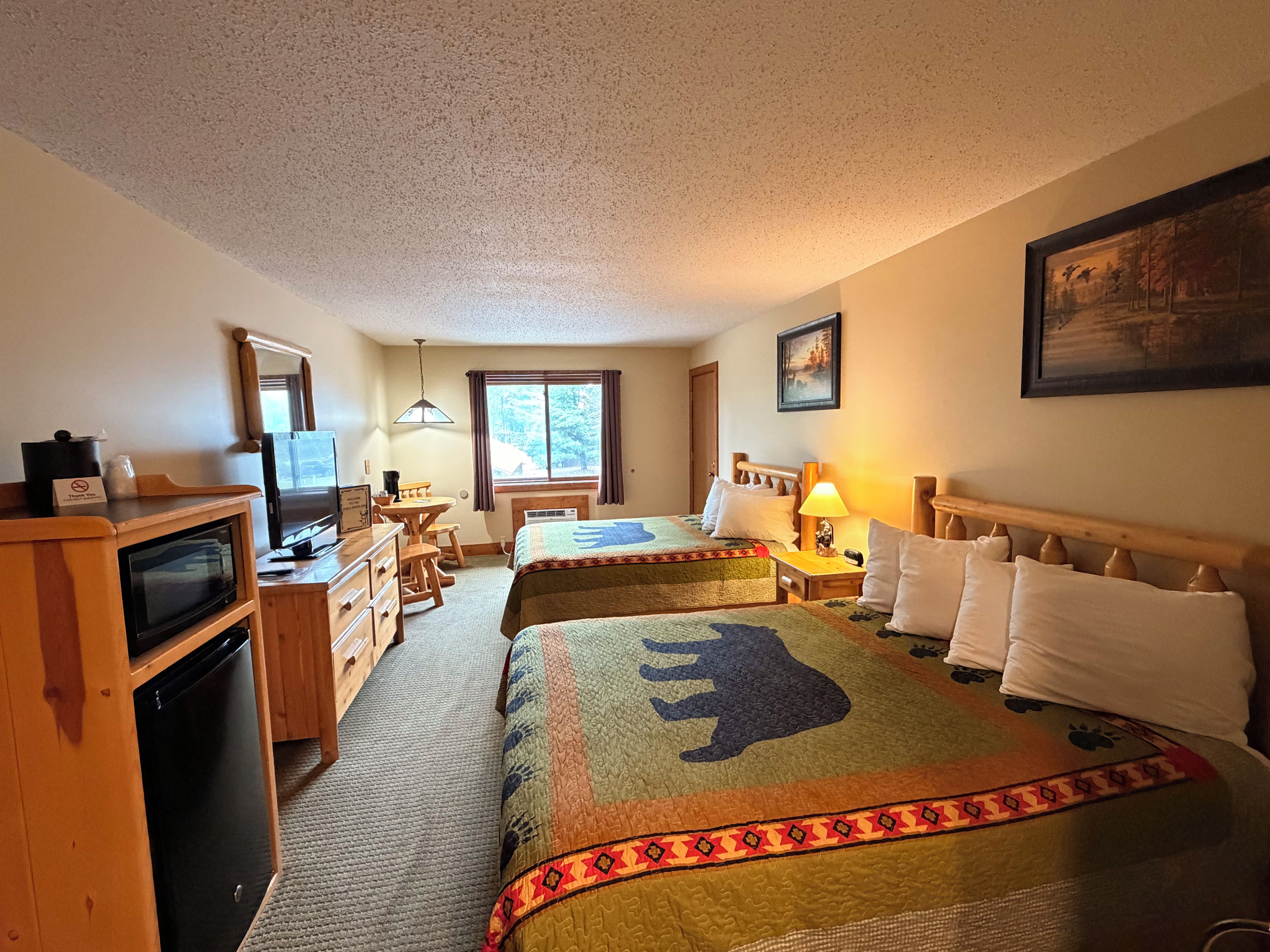 Habitación de hotel con dos camas, un escritorio, un televisor y una ventana con cortinas.