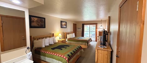 Una habitación de hotel con dos camas, un baño, un escritorio con ordenador y una puerta.