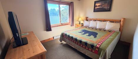 A hotel room with a bed, a desk, a television, a window with curtains, and a painting on the wall.