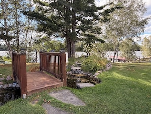A wooden bridge leading to a dock over a small stream, surrounded by lush greenery and trees. - Eagle River Inn and Resort  (Eagle River)