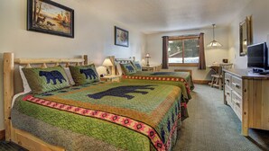 A room with two beds, each with a bear-themed quilt, a wooden desk with a television, and a window with a view of trees. - Eagle River Inn and Resort  (Eagle River)
