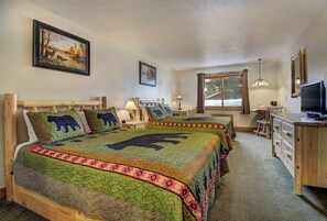 A room with two beds, each with a bear-themed quilt, a wooden desk with a television, and a window with a view of trees. - Eagle River Inn and Resort  (Eagle River)