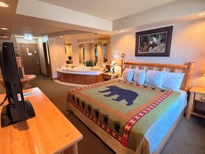 A hotel room with a large bed, a wooden desk, a television, a bathroom with a bathtub, and a framed picture on the wall. - Eagle River Inn and Resort  (Eagle River)
