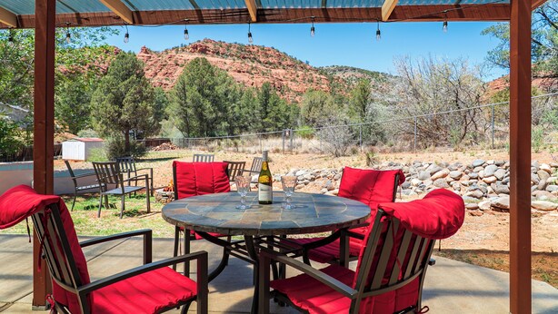 Un espace extérieur abrité, avec une table et des chaises, offrant une vue sur un paysage montagneux.