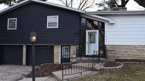 A two-story house with a black exterior, a white garage door, and a stone foundation. - The Birchwood - 1 mile from Lambeau Field! (Green Bay)