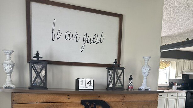 A reception desk with a wooden panel design, a large decorative letter 'D', a framed sign saying "be our guest", and a small calendar displaying "14 APRIL". - 4-bedroom house in fantastic Mountain View with AC, WiFi!!!! (Mountain View)