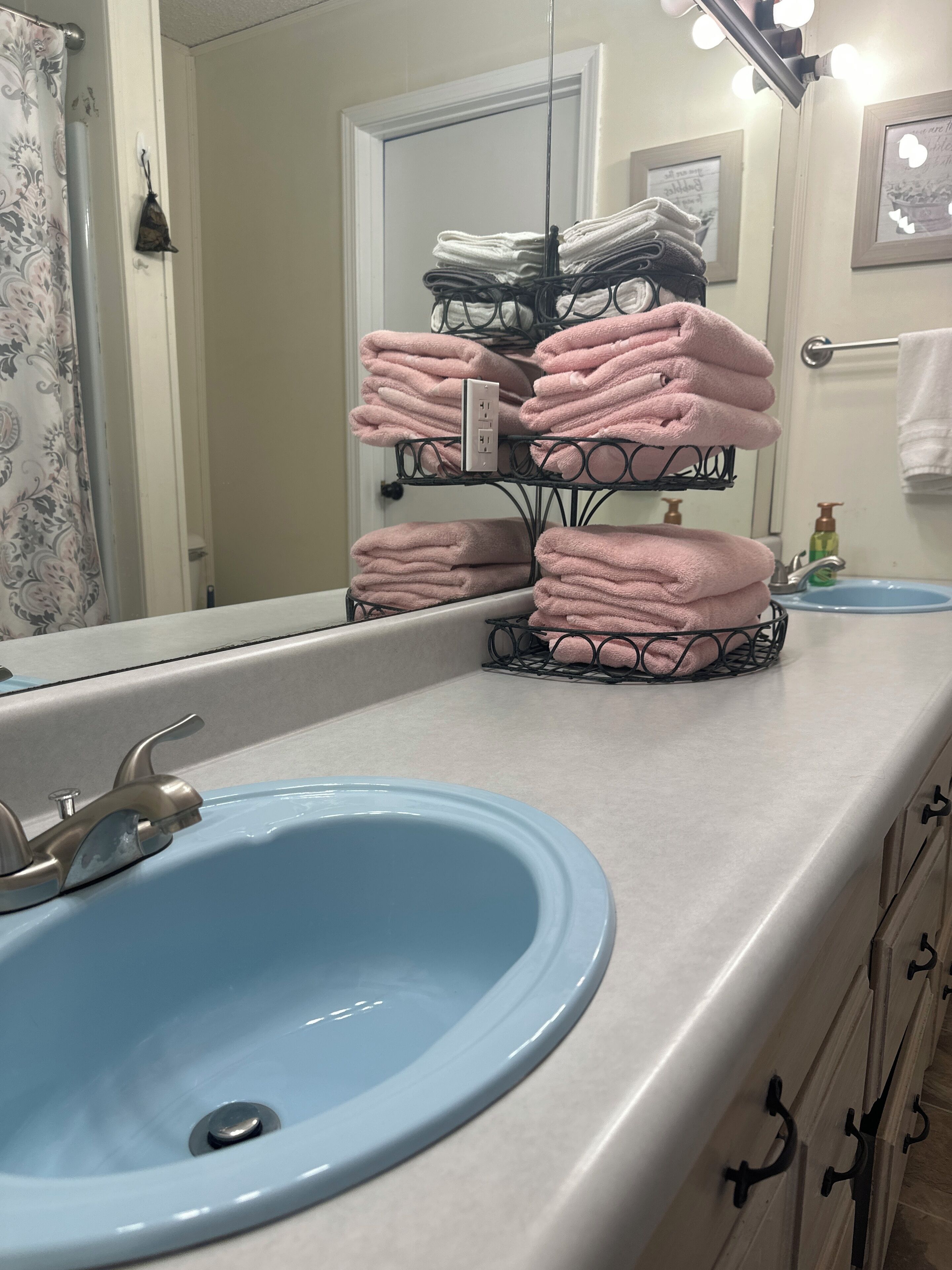 A bathroom with two sinks, a towel rack with pink towels, a mirror, and a door.
