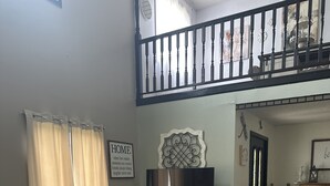 A living room with a patterned armchair, a flat-screen TV, a sofa, and a staircase leading to an upper level. - 4-bedroom house in fantastic Mountain View with AC, WiFi!!!! (Mountain View)