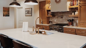 A kitchen with a large island, wooden cabinets, and pendant lighting.