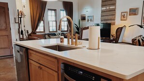 A kitchen with wooden cabinets, a dishwasher, and a built-in oven. There are pendant lights above the counter and a ceiling fan.