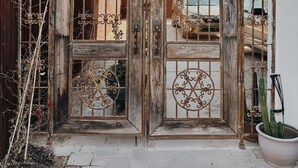 A rustic wooden gate with decorative metalwork, a potted cactus, and a Christmas wreath.