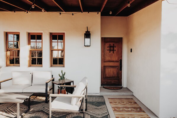 A cozy interior with a sofa, armchair, and coffee table, a wooden door, and a small table with a plant.