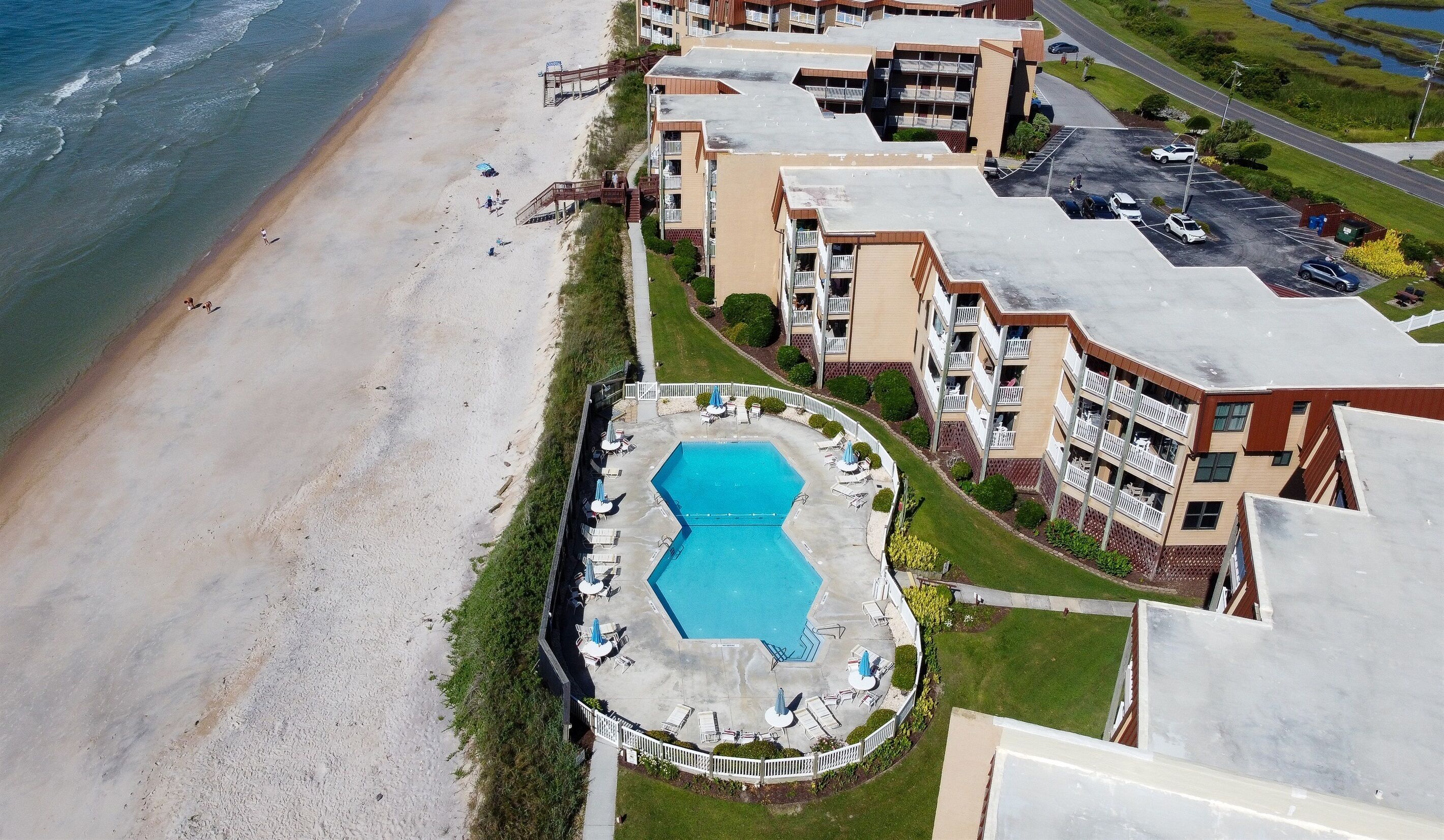 Een hotel aan het strand met een zwembad, toegang tot het strand en meerdere balkons.