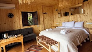 Une chambre dans une cabane en bois, avec un lit, un banc, un canapé et des luminaires suspendus.
