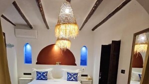 Une chambre à coucher avec un lit, un luminaire suspendu, un tapis à motifs et un miroir.