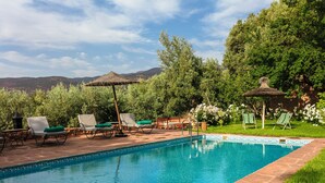 Une piscine avec des chaises longues et une pergola.