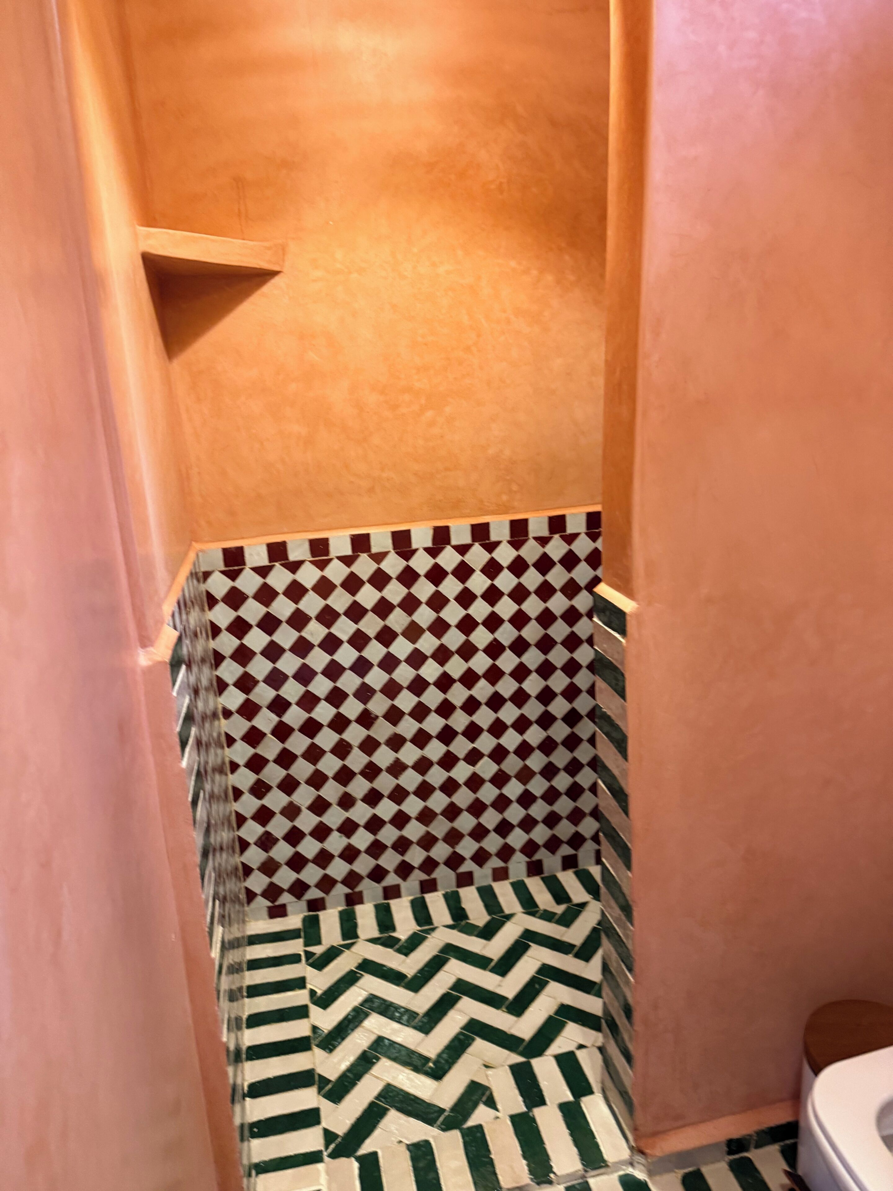 A bathroom with a checkered tile wall, a patterned floor, and a wooden door.