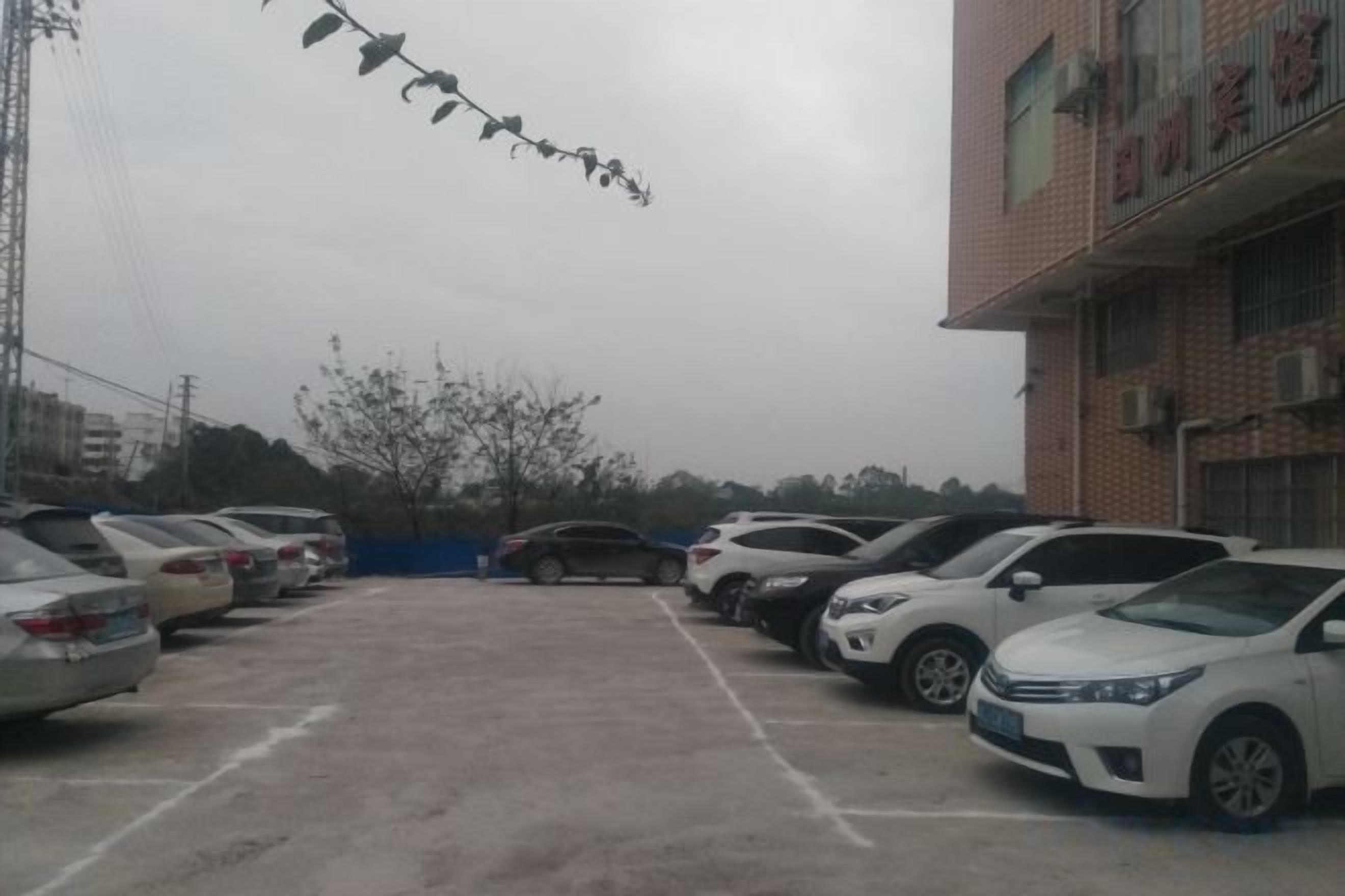 A parking lot with multiple cars, a building with a red brick facade, and a clear sky.