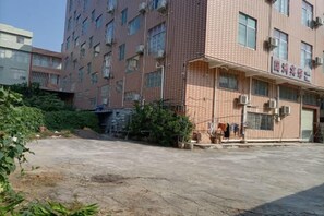 Un edificio de varios pisos con fachada de ladrillo, unidades de aire acondicionado y una entrada visible con un letrero.