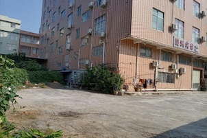 A multi-story building with a brick facade, air conditioning units, and a visible entrance with a sign.