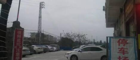 A parking lot with multiple cars, a sign indicating a parking area, and a building with signage.