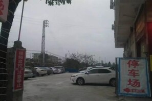 A parking lot with multiple cars, a sign indicating a parking area, and a building with signage. - Pingnan Guozhou Hotel (Pingnan)