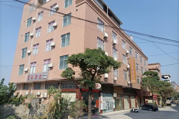 A multi-story building with a brick facade, several ground-level shops, and a tree in front. - Pingnan Guozhou Hotel (Pingnan)