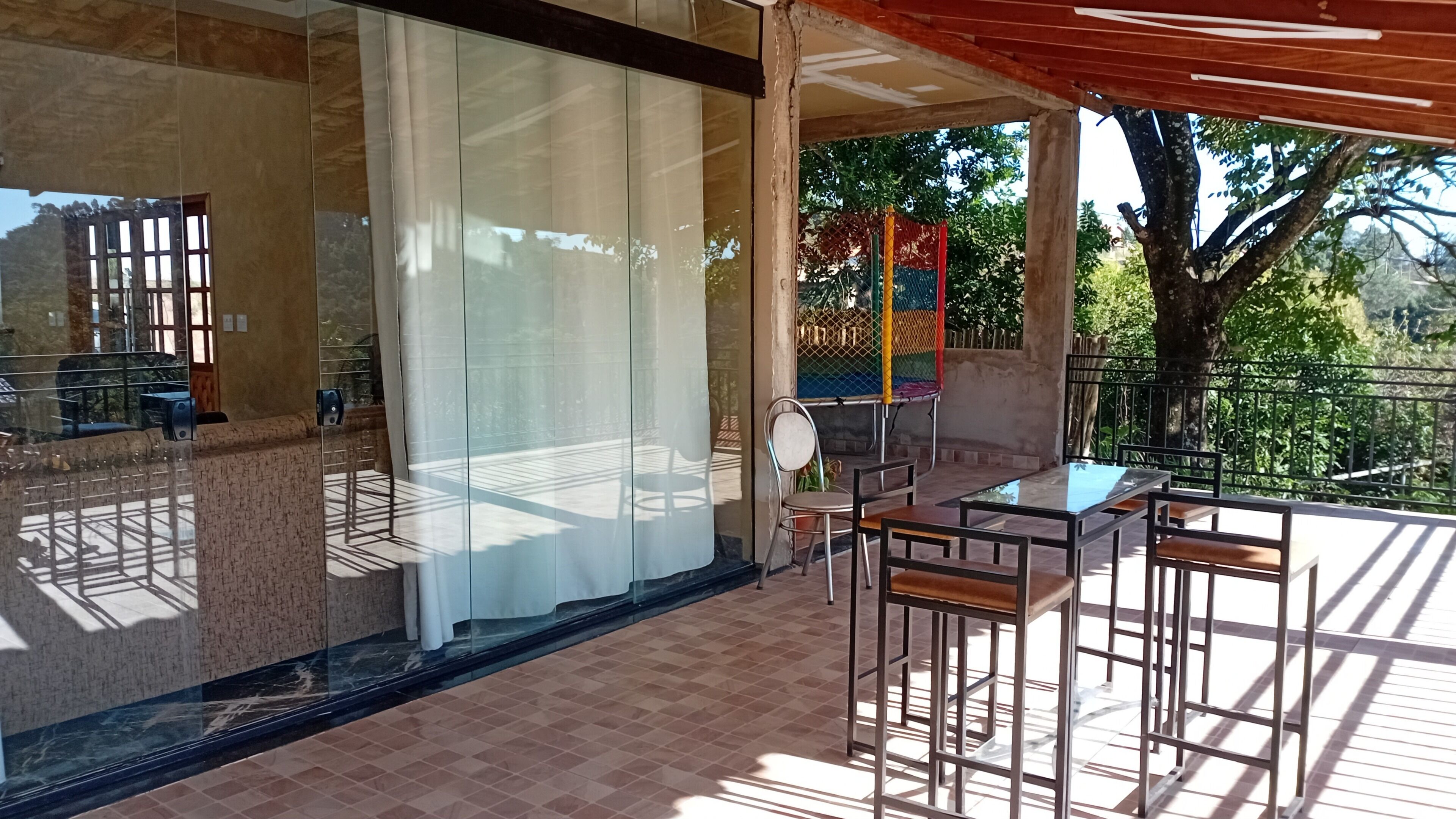 Ein Balkon mit Glasbrüstung, Sitzgelegenheit im Freien und Blick ins Grüne.