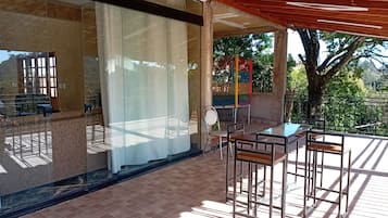 Ein Balkon mit Glasbrüstung, Sitzgelegenheit im Freien und Blick ins Grüne.