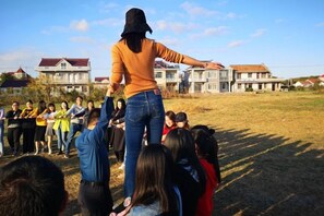 A person standing on a grassy field with a group of people below, in front of residential buildings. - An Hengsha Isiand Resort Hotel (Shanghai)
