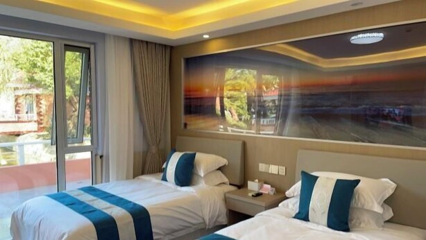 A hotel room with two beds, a large window with a view, and a ceiling light fixture. - An Hengsha Isiand Resort Hotel (Shanghai)