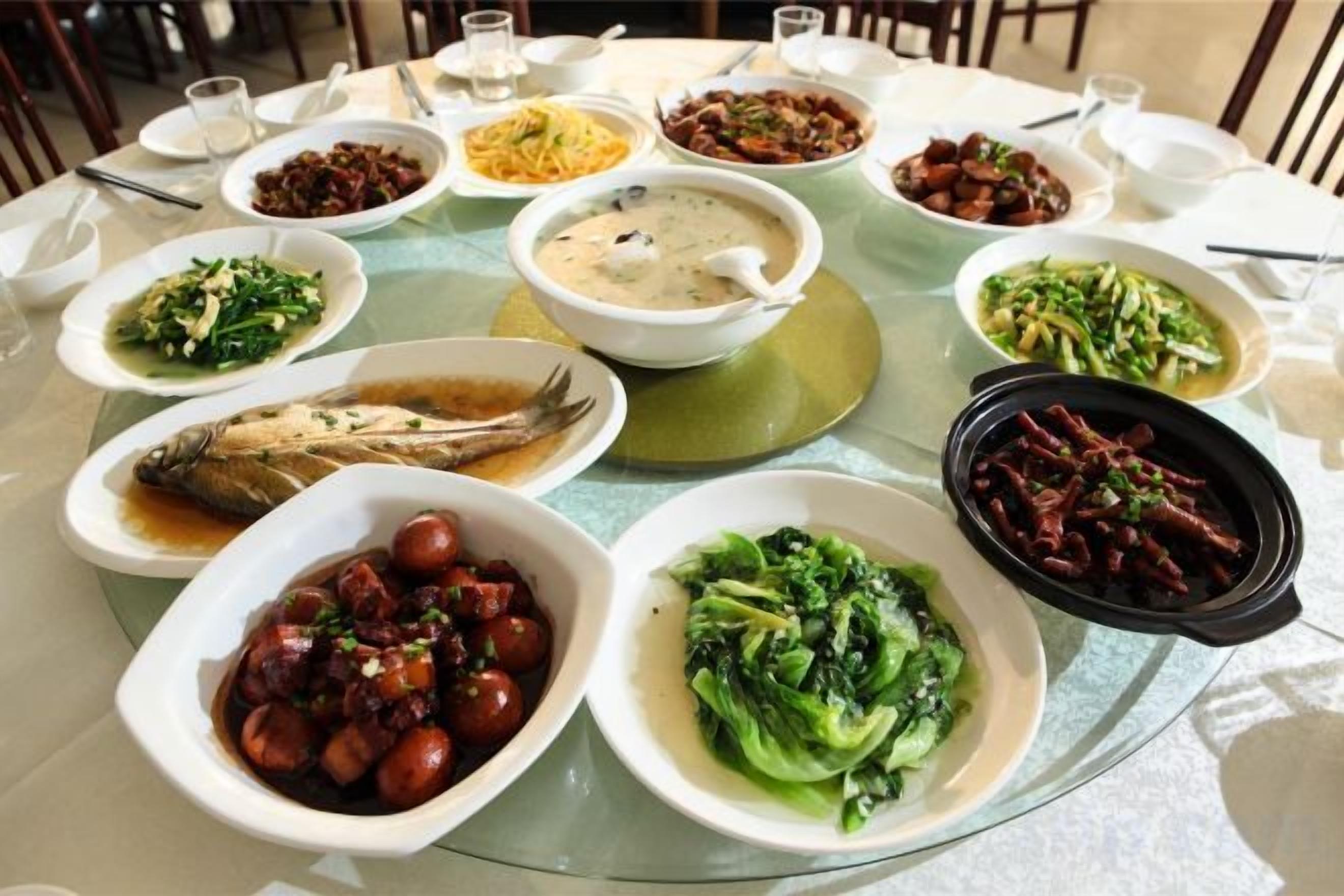 A round dining table with multiple dishes of various foods.